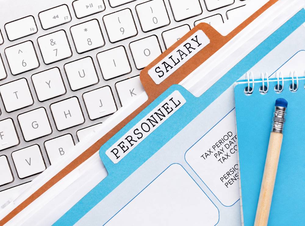 Payroll and personnel documents on a computer keyboard with salary and tax paperwork