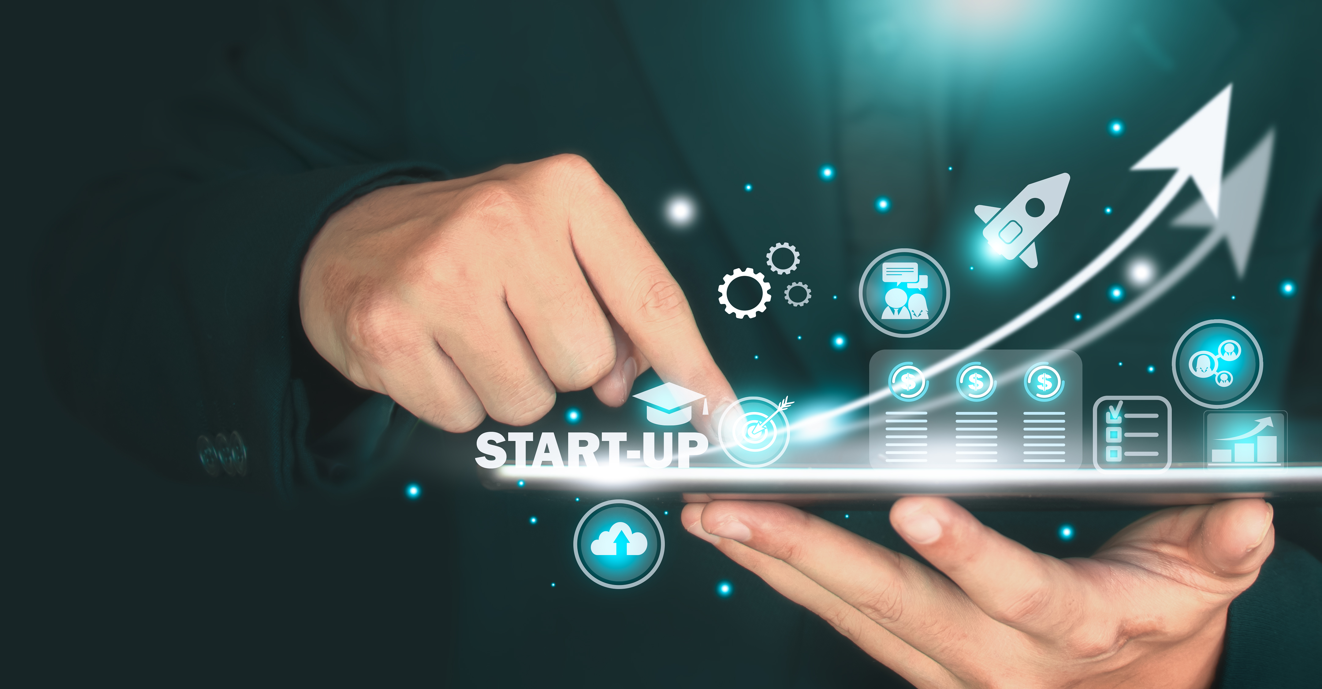 Hands tapping a tablet with glowing startup icons, including a rocket and graphs, on a dark background, conveying innovation and growth.