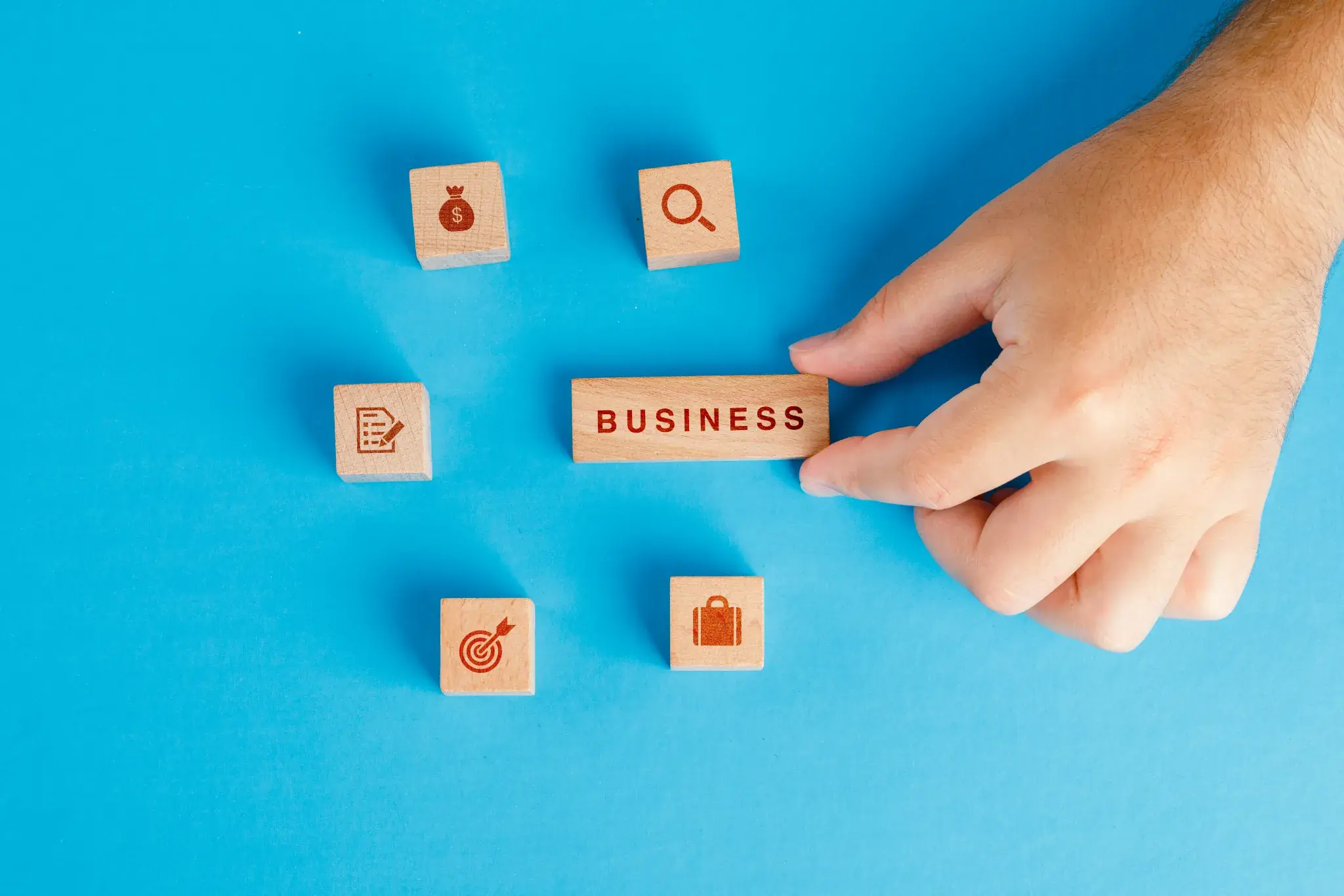 Hand arranges wooden blocks labeled 